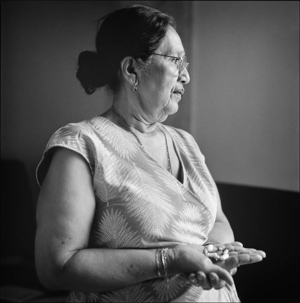 Mujer mayor de perfil sosteniendo varios objetos pequeños en las manos.